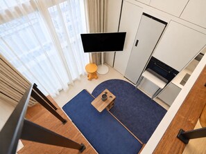 A modern hotel room with a flat-screen TV, a small round table, a sofa, and a kitchen area. - UH FLAT SIGNATURE GANGNAM (Seoul)