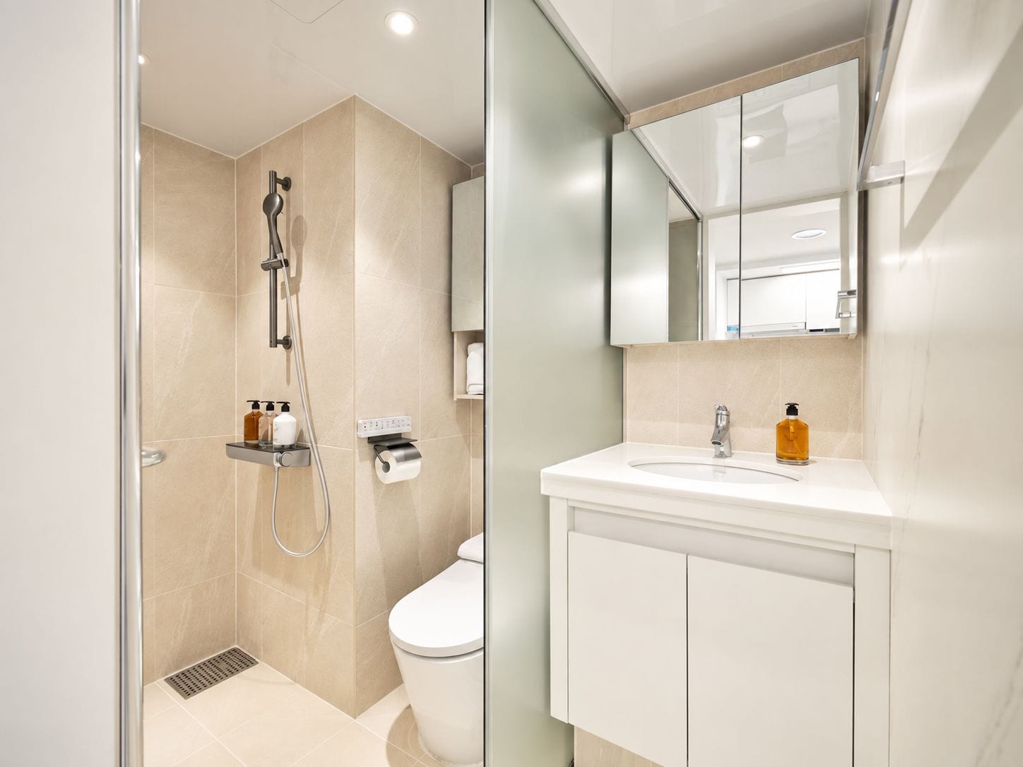A modern bathroom with a glass-enclosed shower, a toilet, and a vanity with a mirror.