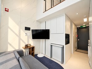 A modern hotel room with a flat-screen TV, a sofa, a small table with a radio, and a fireplace. - UH FLAT SIGNATURE GANGNAM (Seoul)