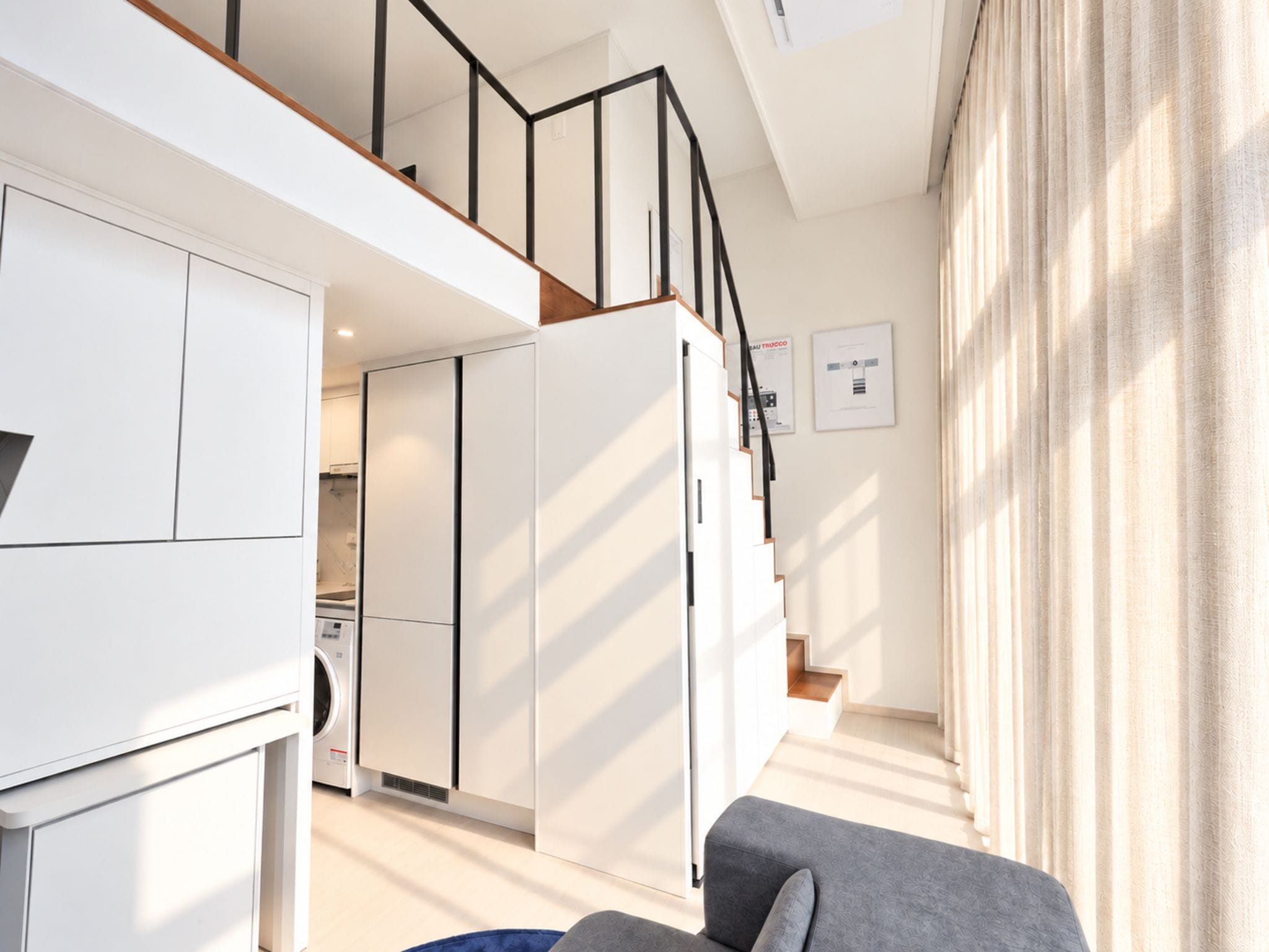 A modern apartment with a kitchen, living area, and a staircase.
