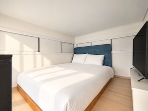 Un dormitorio moderno con una cama grande, un televisor de pantalla plana y suelo de madera.