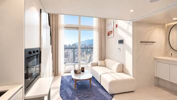 A modern living room with a sofa, a coffee table, and a view of a cityscape through large windows.