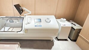 A medical imaging machine in a room with tiled walls and a counter. - UH FLAT SIGNATURE GANGNAM (Seoul)