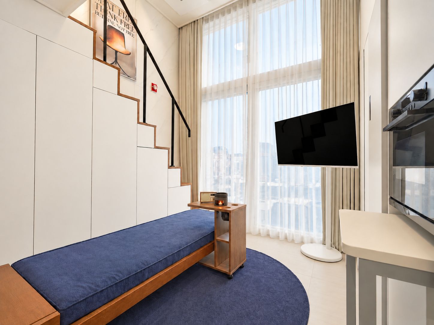 A modern hotel room with a bed, a flat-screen TV, a desk, and a window with curtains.
