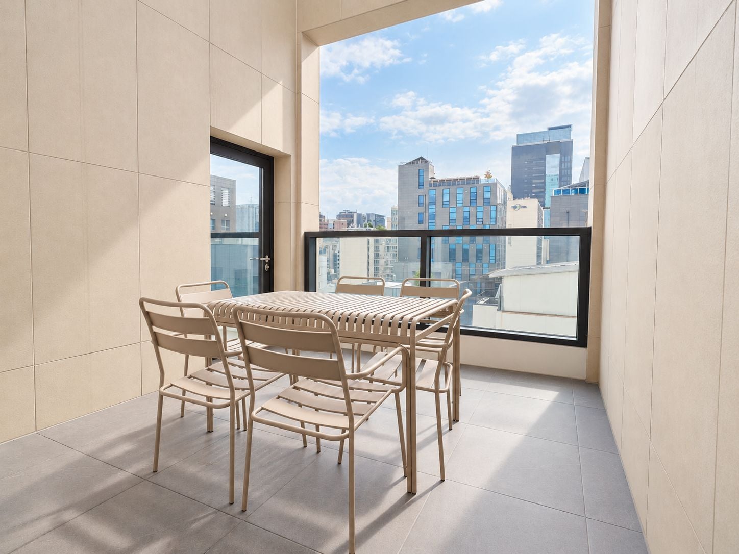 A balcony with a table and chairs, a city view, and a door.