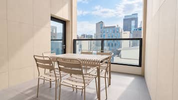 A balcony with a table and chairs, a city view, and a door.