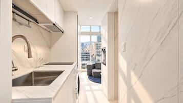 A modern kitchen with a built-in oven and a view of the cityscape through large windows.