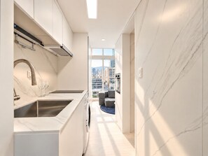 A modern kitchen with a built-in oven and a view of the cityscape through large windows. - UH FLAT SIGNATURE GANGNAM (Seoul)