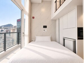 A modern hotel room with a bed, a TV, and a view of the cityscape. - UH FLAT SIGNATURE GANGNAM (Seoul)