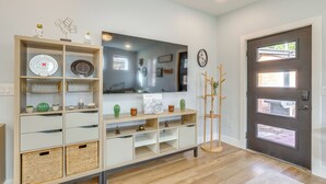 A modern living room with a wooden console table, shelves with decorative items, a large mirror, and a dark wooden door with windows. - 4 Mi to Dtwn Phx: Couples Escape w/ Shared Patio (Phoenix)