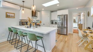 A modern kitchen with a central island, bar stools, stainless steel appliances, and pendant lighting. - 4 Mi to Dtwn Phx: Couples Escape w/ Shared Patio (Phoenix)