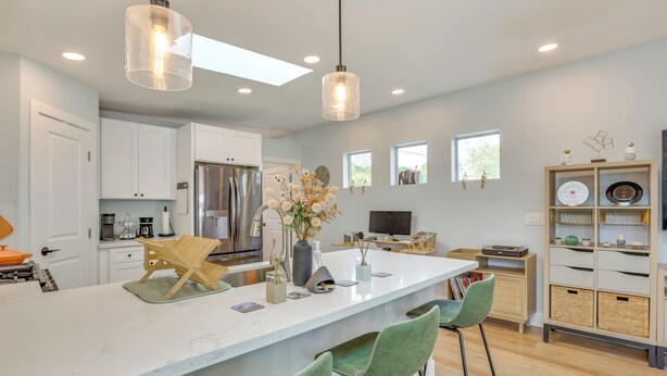 A modern kitchen with white cabinets, a large island with bar stools, a refrigerator, and pendant lighting. - 4 Mi to Dtwn Phx: Couples Escape w/ Shared Patio (Phoenix)