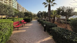 A paved pathway lined with red benches and palm trees, leading towards a residential area with multi-story buildings. - 3-bed apartment in Sliema with sea views (Sliema)