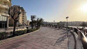A paved walkway with a curved railing, a tree-lined path, and a view of a multi-story building in the background. - 3-bed apartment in Sliema with sea views (Sliema)