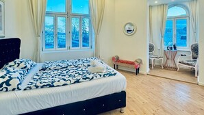 Un dormitorio con una cama grande, una ventana, una mesita con sillas y vistas al exterior.