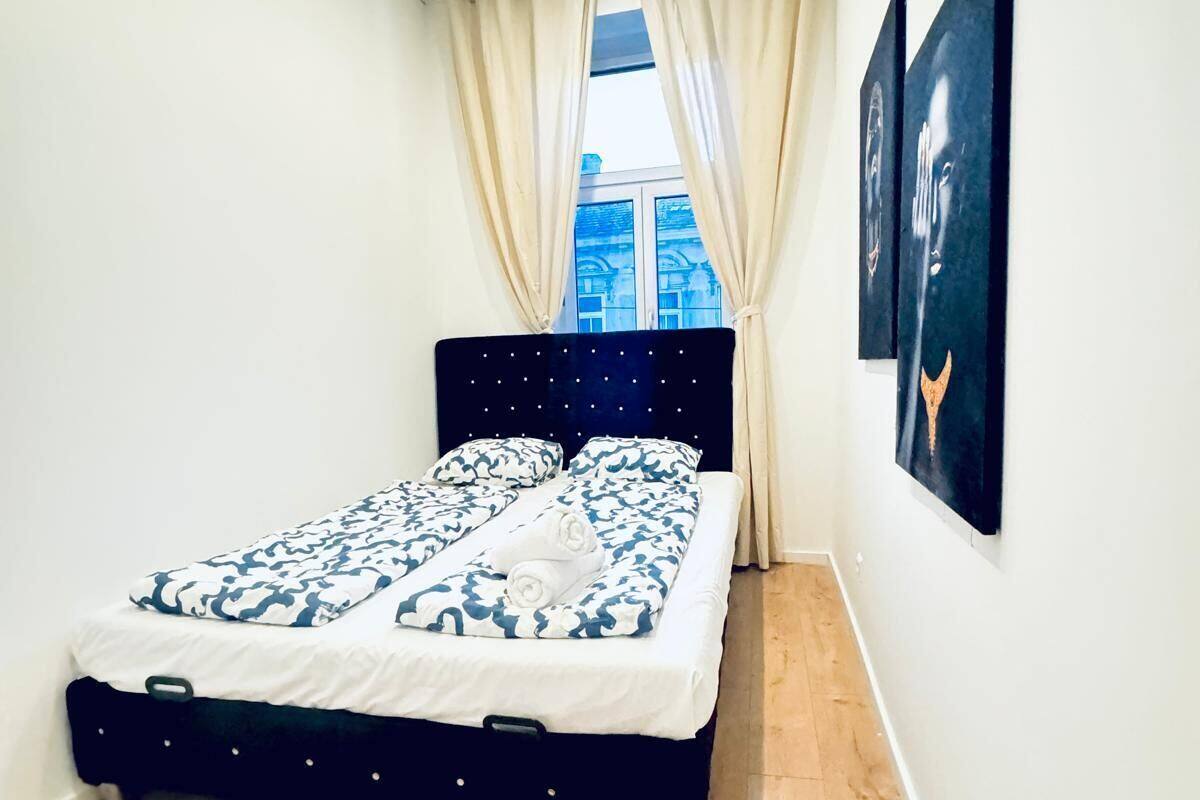 A bedroom with a bed, a window with curtains, and two wall-mounted artworks.