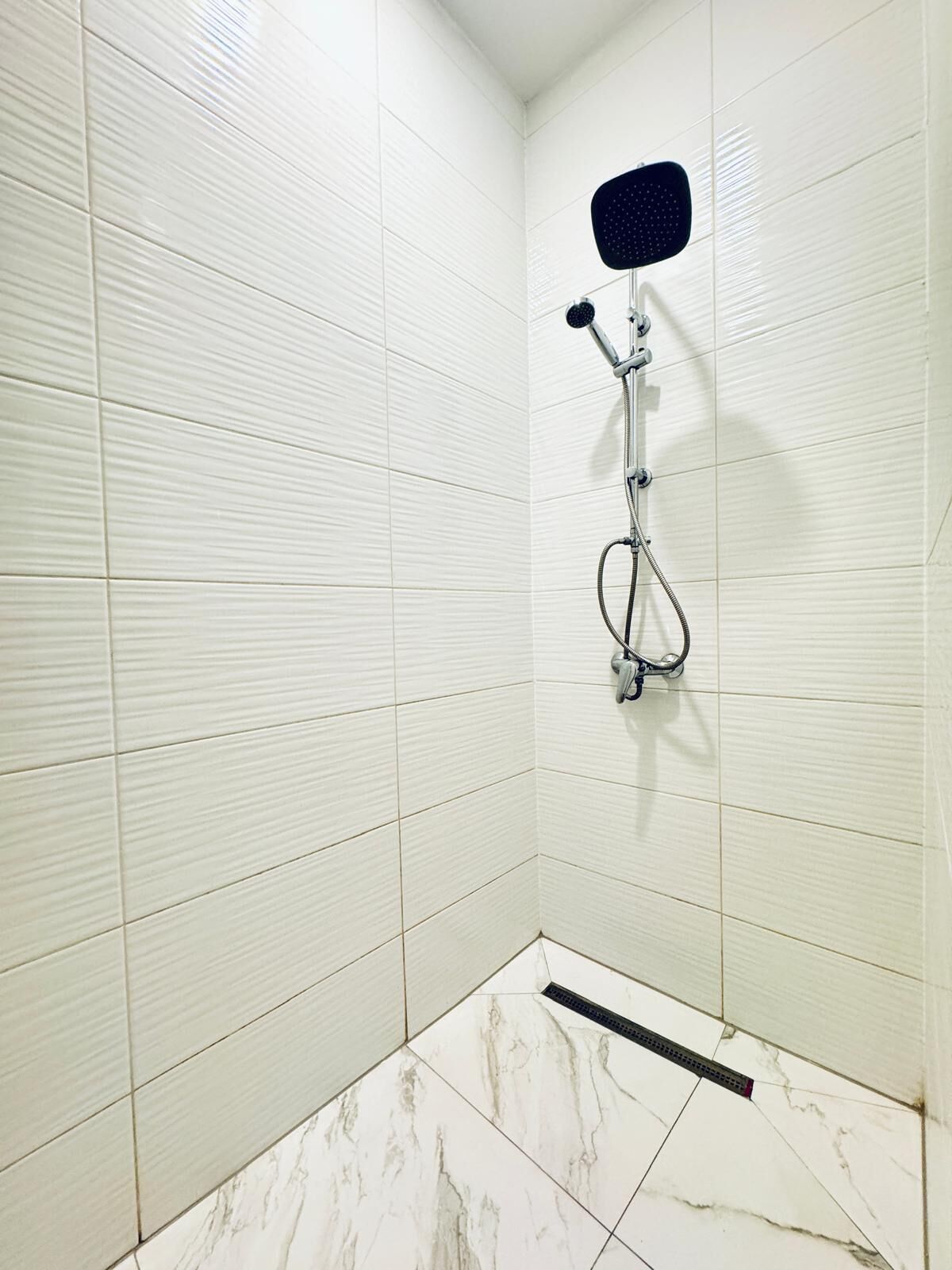 Eine Dusche mit Handbrause und einer fest installierten Bedienarmatur.