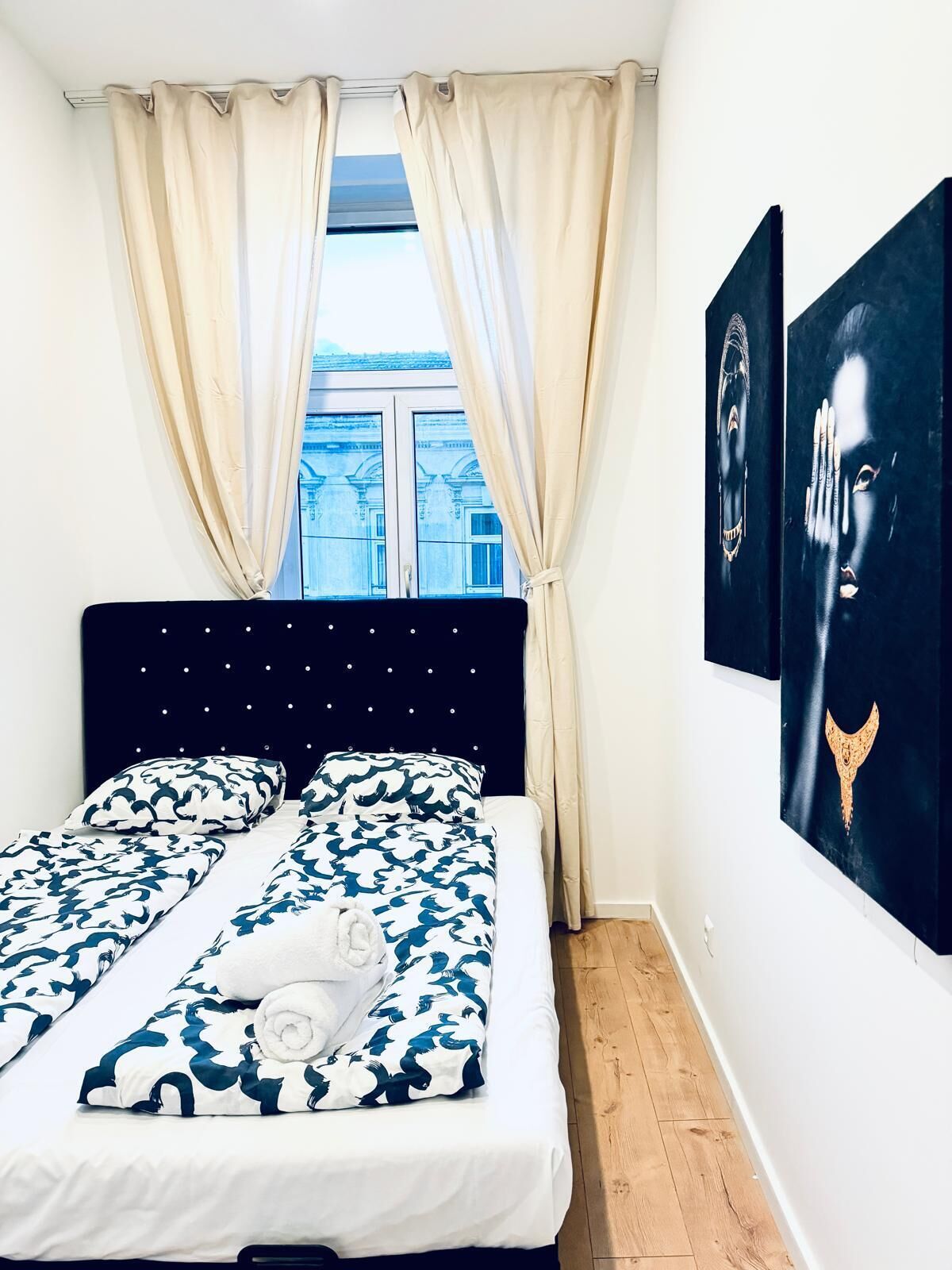 Un dormitori amb un llit, cortines i una obra d'art a la paret.
