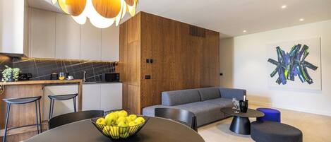 A modern living room with a round table, a grey sofa, and a unique abstract painting on the wall.