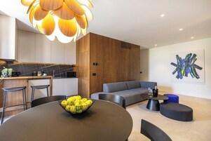 A modern living room with a round table, a grey sofa, and a unique abstract painting on the wall.