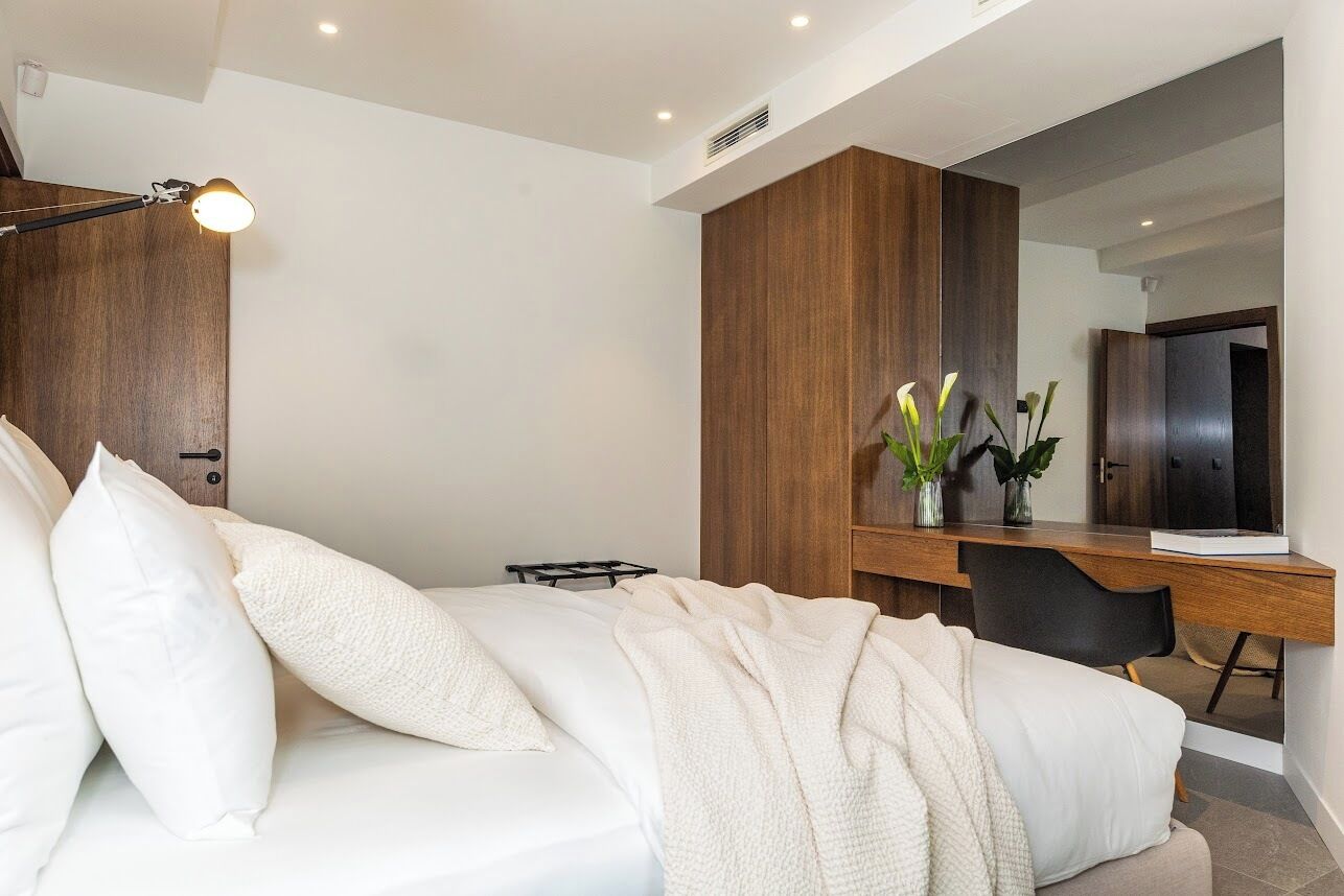 A modern bedroom with a bed, bedside table, and a desk with a chair.