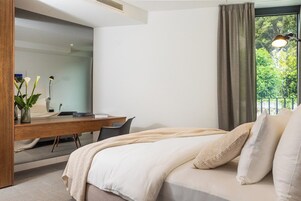 A modern bedroom with a large bed, a desk, and a chair.