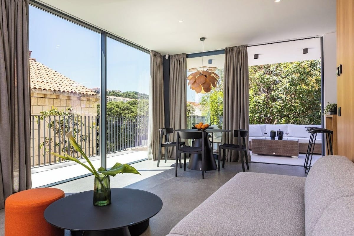 A modern living room with a sofa, a round table with a vase, and a dining area with chairs and a table.