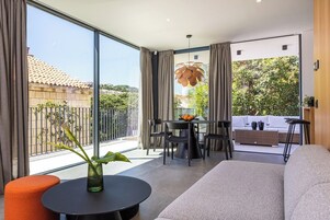 A modern living room with a sofa, a round table with a vase, and a dining area with chairs and a table.