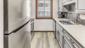 A kitchen with a stainless steel refrigerator, a window with blinds, a herringbone-patterned backsplash, and a sink with a faucet. - Walk to Ocean: Condo w/ 3 Pools in Myrtle Beach (Myrtle Beach)