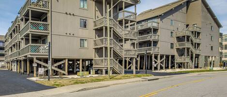 A multi-story hotel with outdoor balconies and a parking area.