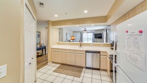 A modern kitchen with a built-in dishwasher, a large window, and a ceiling fan. - On Thousand Hills Golf Course: Condo w/ Sunroom (Branson)
