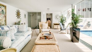 A spacious living room with a large sofa, a dining area, and a pool. - 3bed With Indoor Pool and Sea Views The Sanctuary (Cape Town)