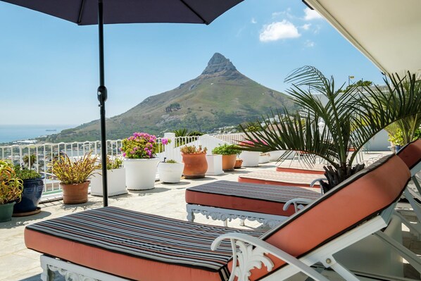 Relax on the terrace with lounge chairs and lush greenery, taking in the breathtaking view of the mountain peak.