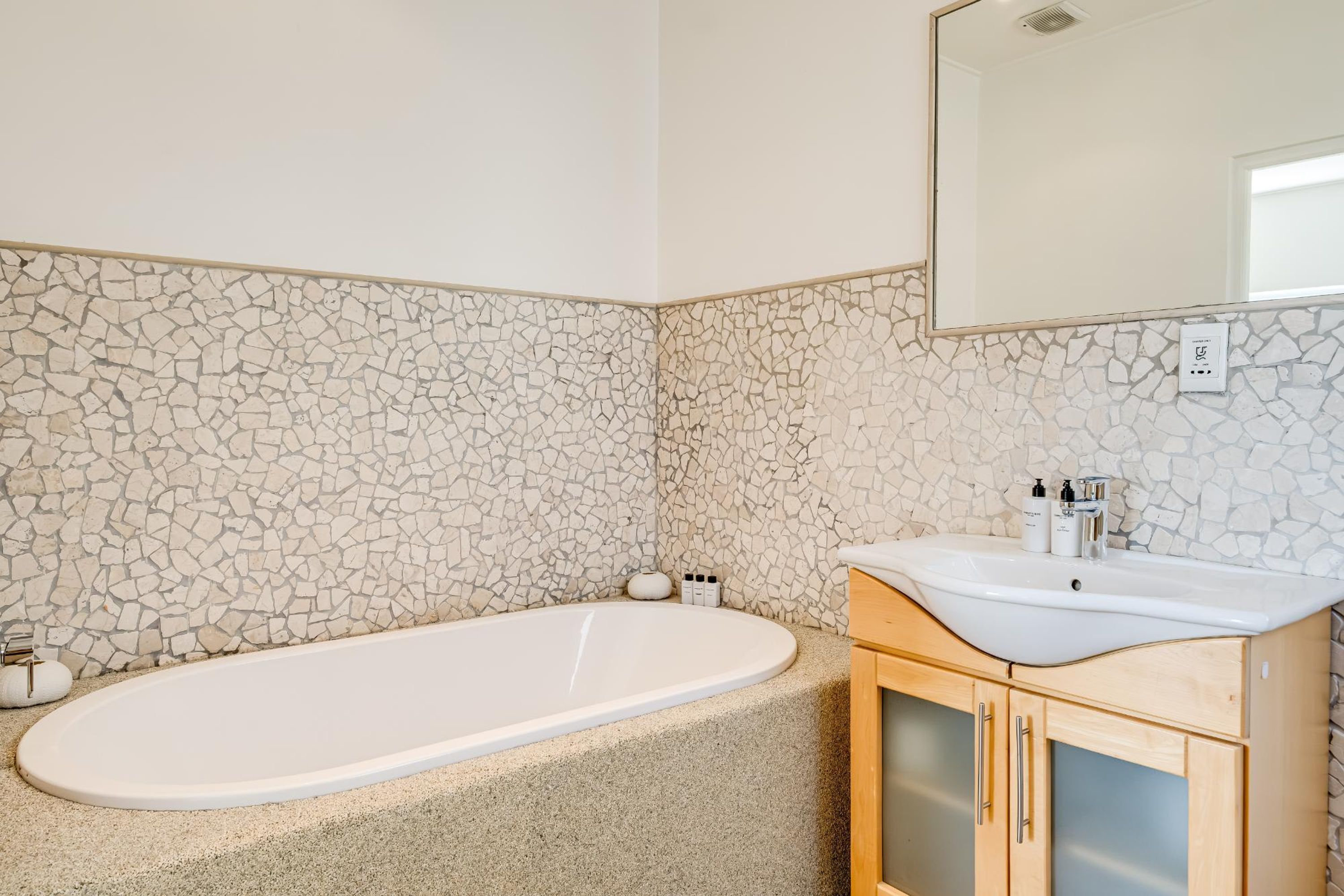A bathroom with a bathtub, a sink, and a mirror.