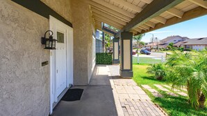 A covered porch with a concrete floor, a white door, and a black lantern.