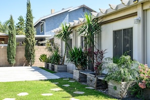 A residential property with a well-maintained lawn, stone pathways, and various potted plants. - Spacious Family Retreat w Garden Modern Comfort (Ontario)