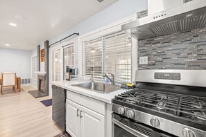 A modern kitchen with a stainless steel range, a double sink, and a built-in oven. - Spacious Family Retreat w Garden Modern Comfort (Ontario)