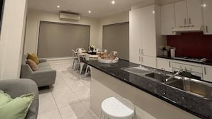 Una cocina moderna con una isla central, armarios blancos y una zona de comedor con sofá y sillas.