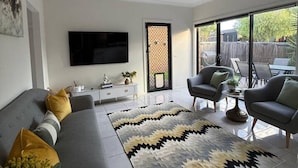 Una sala de estar moderna con un sofá gris, dos sillones, una mesa de centro y un tapete grande.