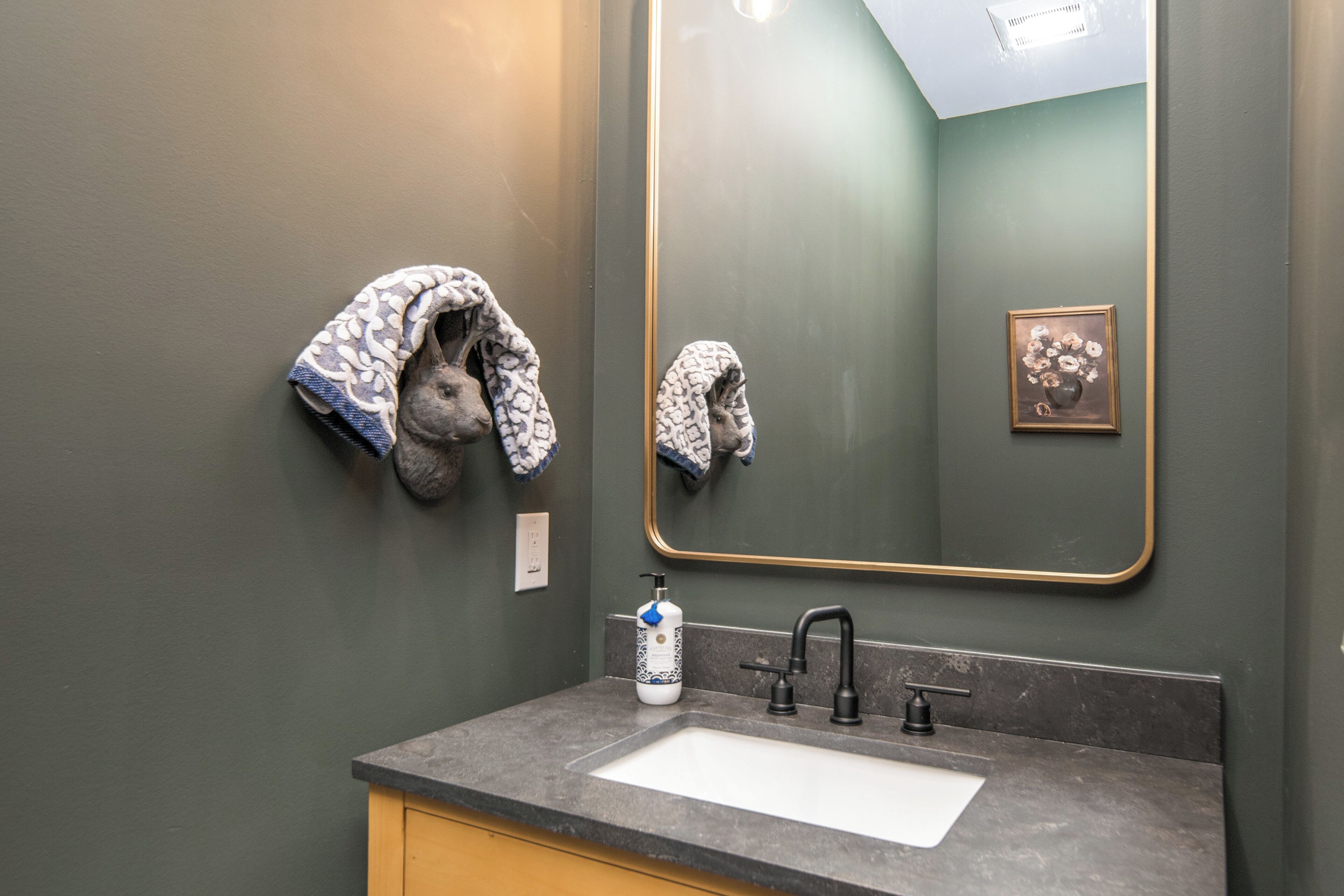 Un bany amb un mirall gran, un lavabo i tovalloles penjades a la paret.