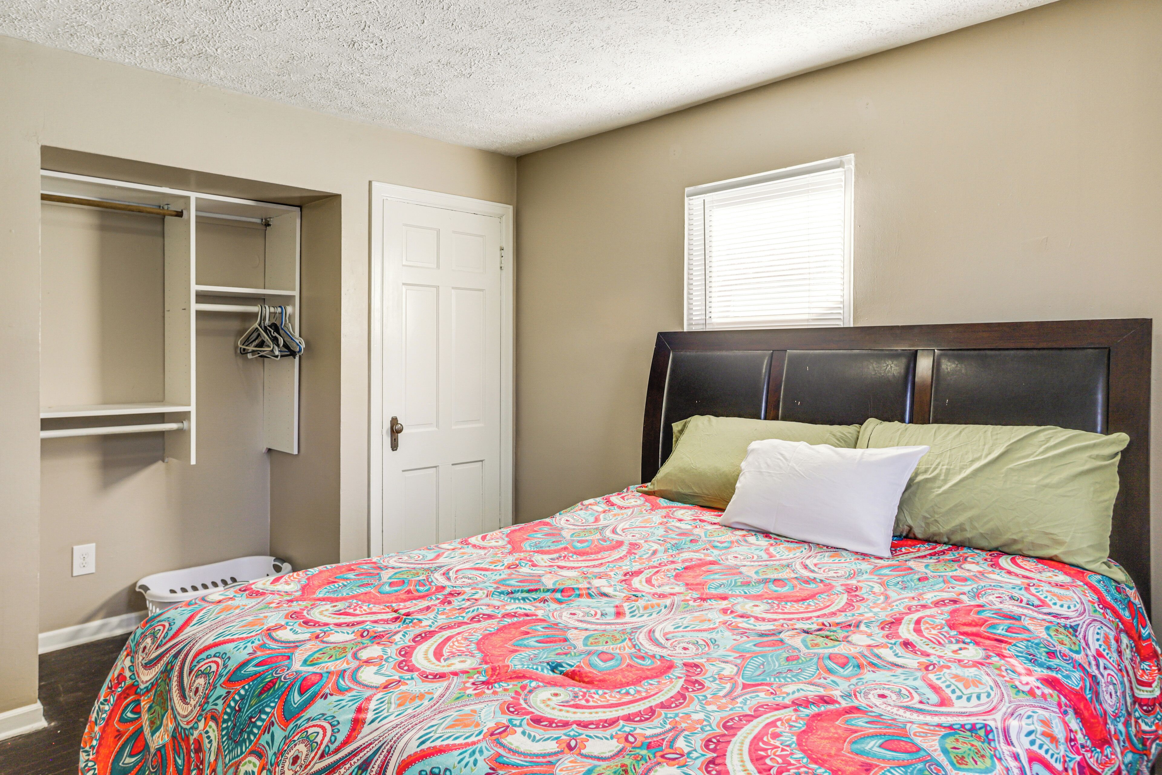 A bedroom with a bed, a closet, a window, and a door.