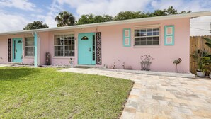 A pink building with turquoise accents, a well-maintained lawn, and a stone pathway leading to the entrance. - 4 Mi to Beaches: Vibrant Stuart Villa w/ Patio! (Stuart)