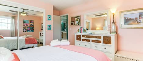 A bedroom with a bed, a dresser, a mirror, and a ceiling fan.