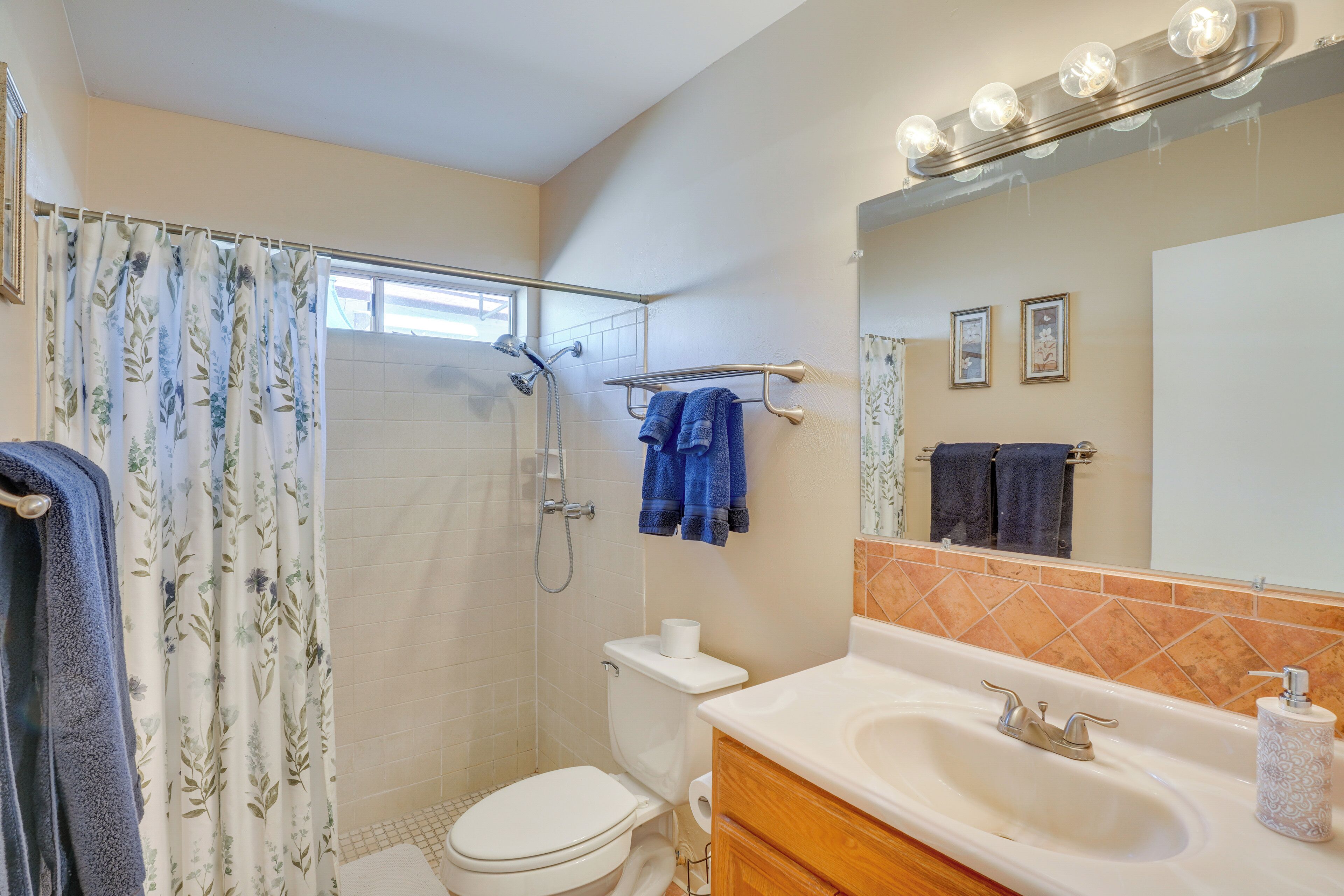 A bathroom with a shower, toilet, sink, and vanity.