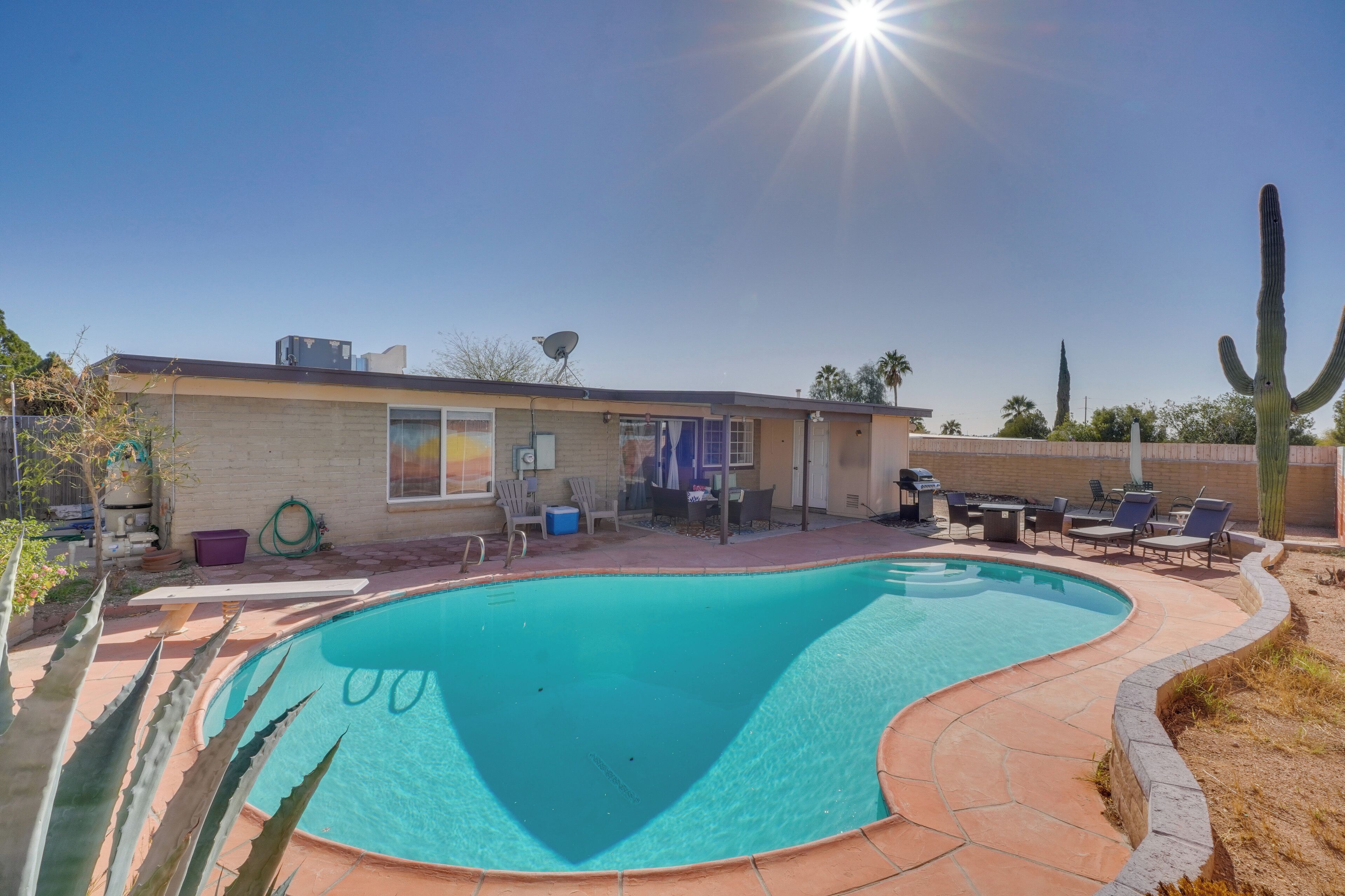 A swimming pool with a curved edge, surrounded by a patio area with outdoor furniture.