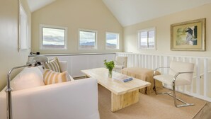 A modern living room with a high ceiling, a ceiling fan, a large window, a white sofa, a wooden coffee table, and a framed painting on the wall. - Near Hiking: Dog-friendly Studio in Los Cerrillos (Cerrillos)