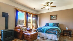 A bedroom with a bed, a leather chair, a radiator, and a window with curtains. - Mtn-view Getaway w/ On-site Trails in Fairplay! (Fairplay)