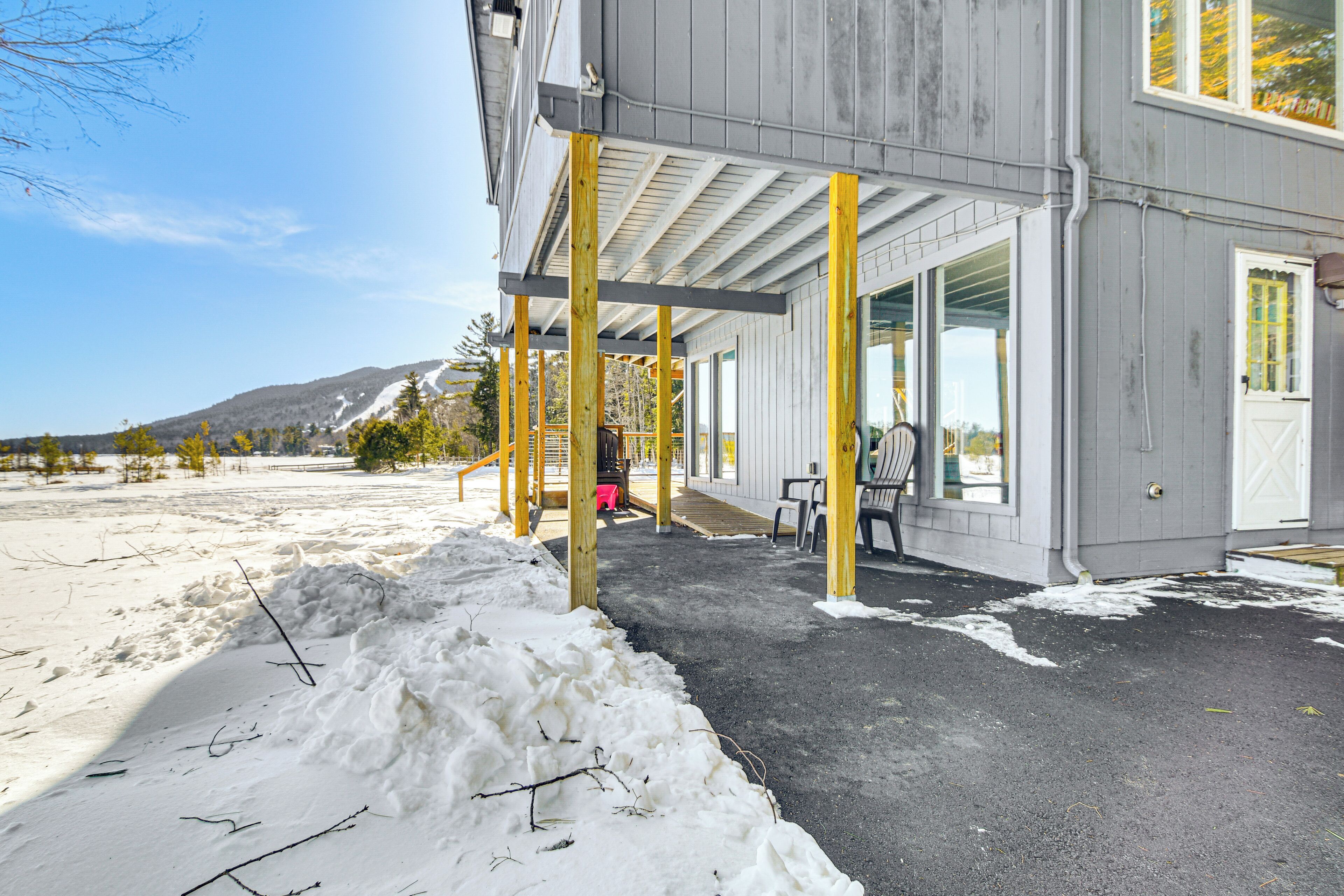 Um edifício com varanda coberta, rampa para cadeiras de rodas e vista para uma paisagem nevada.