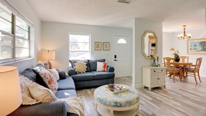 A living room with a sofa, ottoman, and dining table with chairs. - Townhome Near Hobe Sound Beach, Hiking & Golfing! (Hobe Sound)
