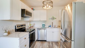 A modern kitchen with white cabinets, stainless steel appliances, and a wooden floor. - Townhome Near Hobe Sound Beach, Hiking & Golfing! (Hobe Sound)